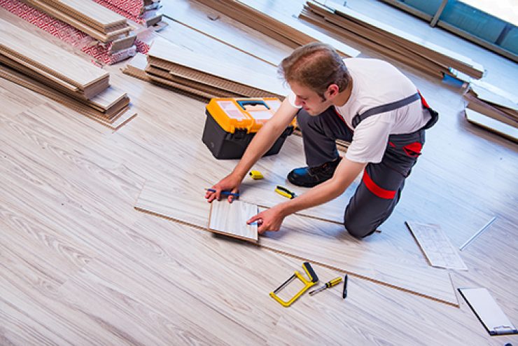 Man laying laminate flooring in construction concept